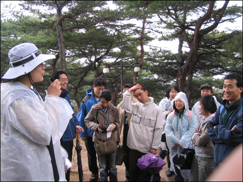 해설사의 설명을 듣고 있는 관람객들. 첫 데뷔한 해설사가 설명을 까먹고 컨닝 하겠다고 실토하자 다함께 긍정하면서 웃고 있다 